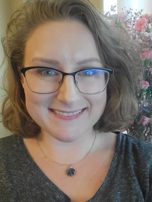Image of Megan with short, light brown hair, wearing glasses and smiling