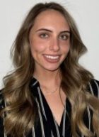 Veronica has long, light brown hair and is smiling while wearing a black and white striped shirt