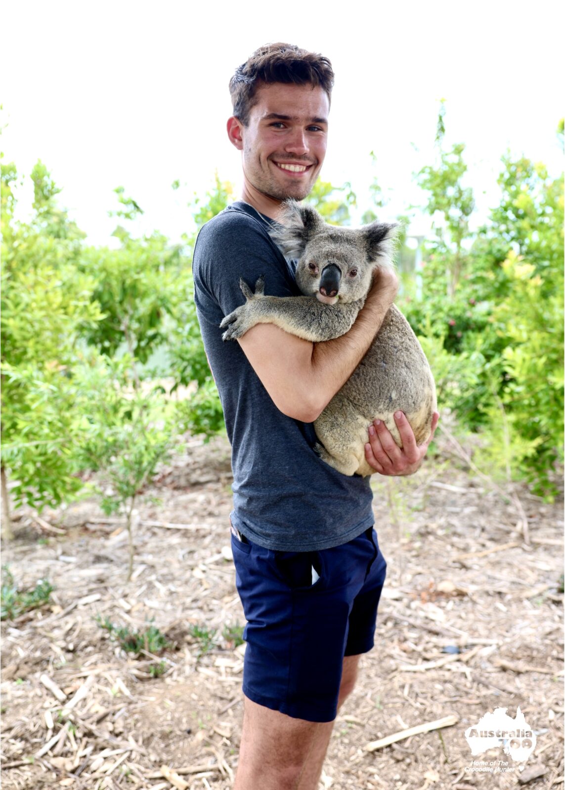 Ryan is holding a koala and smiling. 