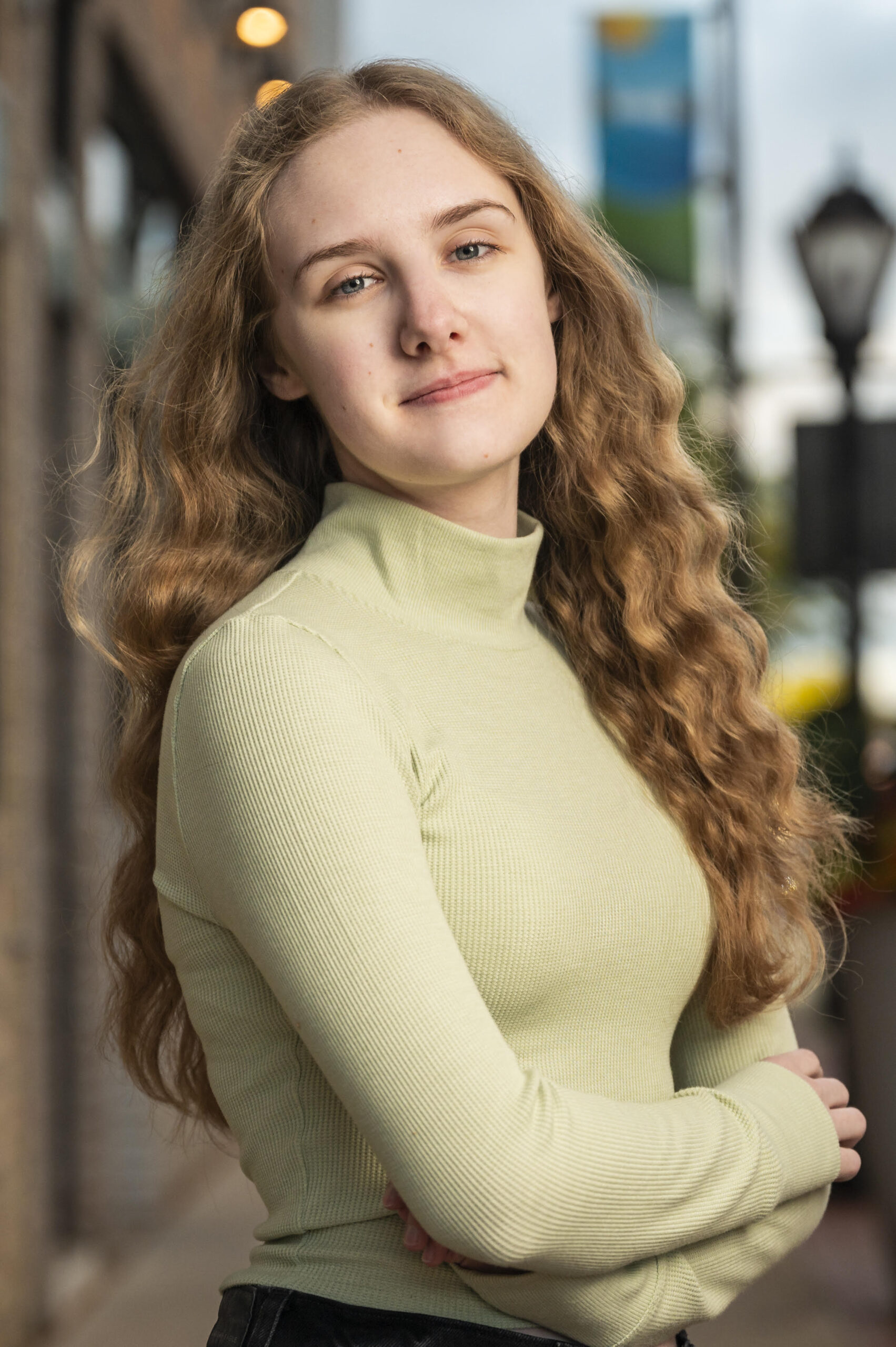 Katelyn is wearing a green turtleneck with long, wave hair. 