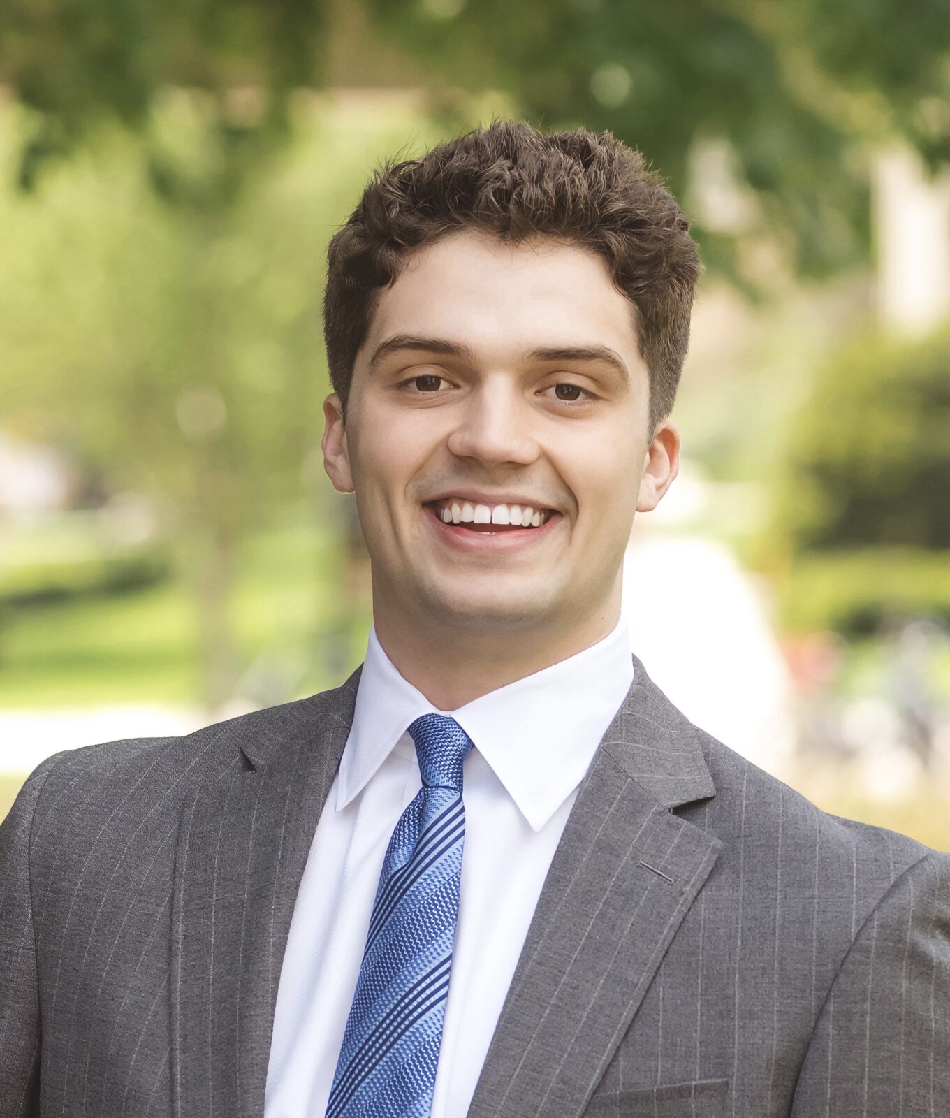 Ethan is wearing a suit and is smiling.